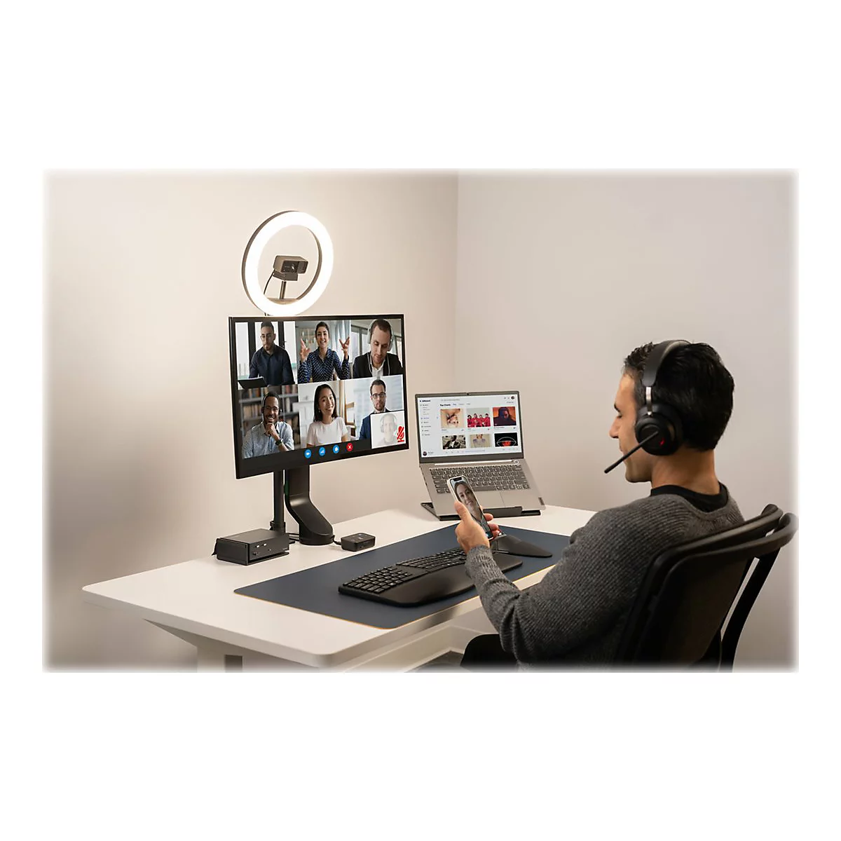 Homme avec casque et tÃ©lÃ©commande lors d'une vidÃ©oconfÃ©rence au bureau. L'Ã©cran affiche plusieurs interlocuteurs.