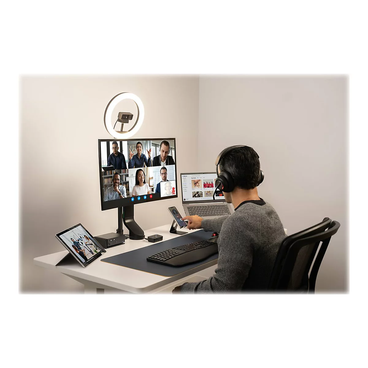 Personne en appel vidÃ©o avec PC, tablette et accessoires. Anneau lumineux en arriÃ¨re-plan.