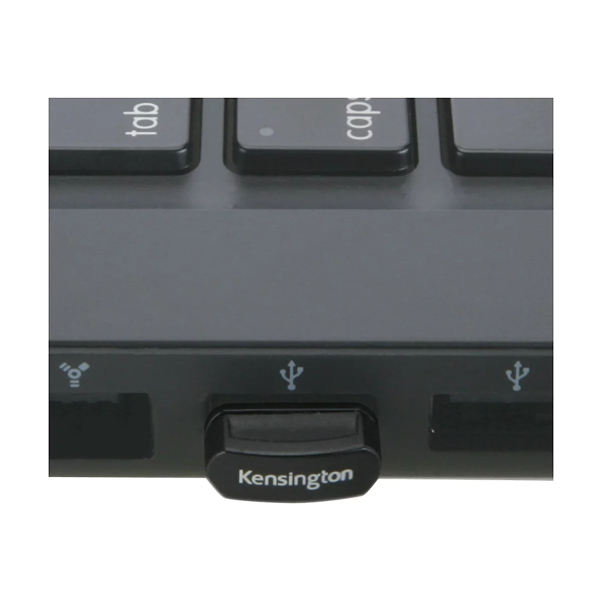 Nahaufnahme eines schwarzen USB-Empfängers mit dem Schriftzug "Kensington" auf der Unterseite. Er steckt in einem Laptop.