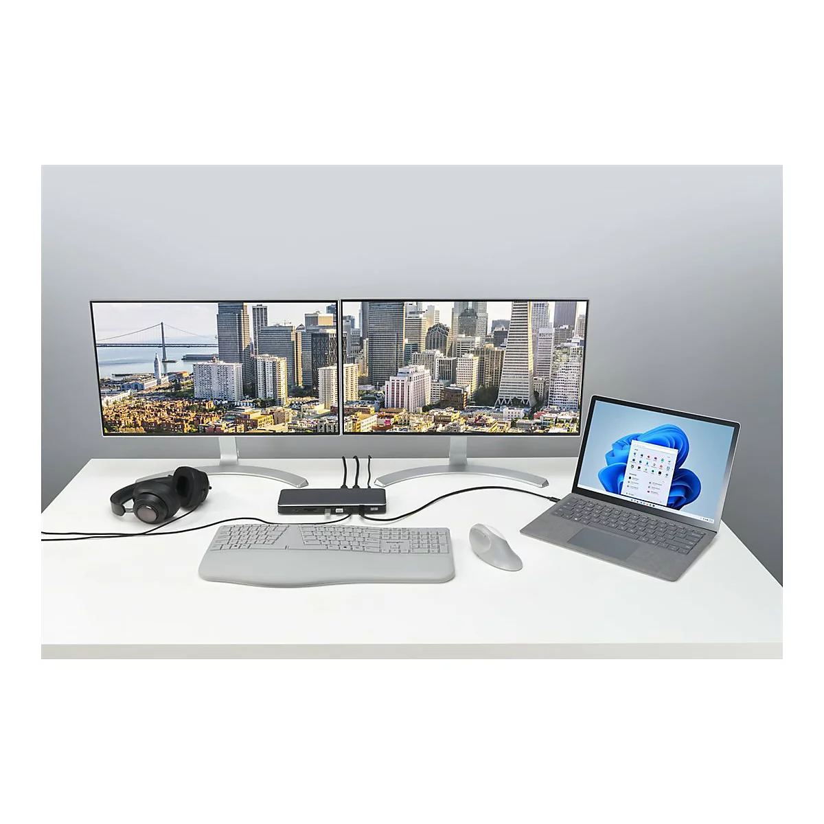 Schreibtisch mit zwei Monitoren, Laptop, Tastatur, Maus, Headset und Dockingstation.