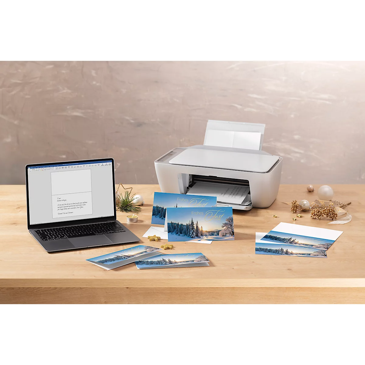 Printer drukt kerstkaarten af. Laptop, kaarten en decoratie op houten tafel.