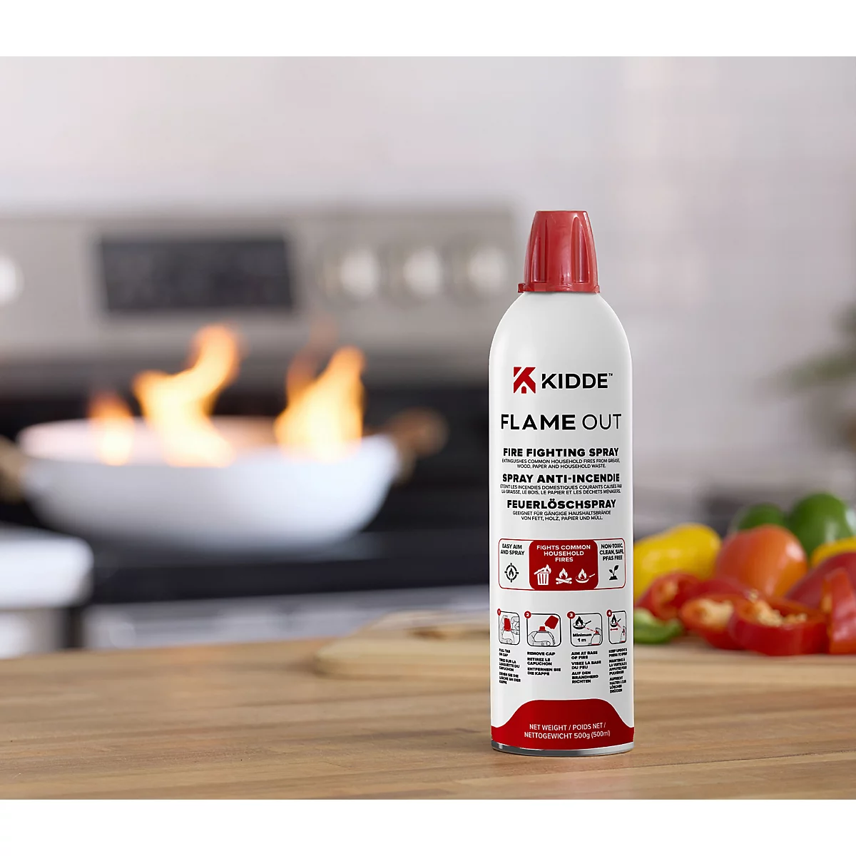 Kidde Flame Out Feuerlöschspray auf einer Küchenarbeitsplatte vor brennender Pfanne.