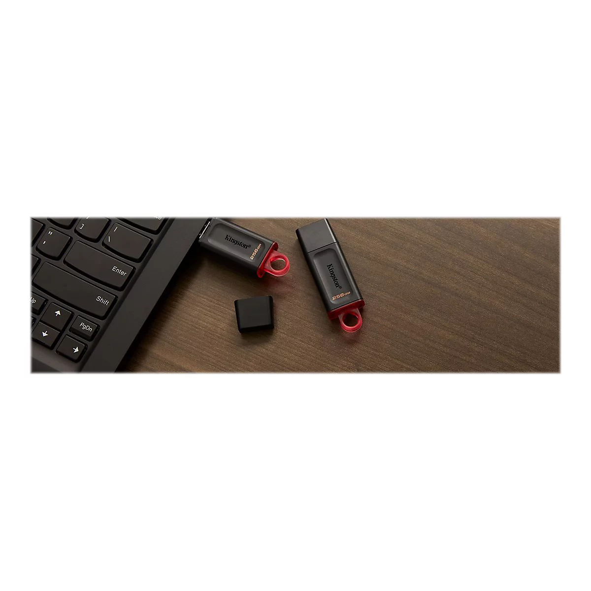 Zwei USB-Sticks mit rotem Ring und schwarzer Kappe liegen auf einem Holzbrett neben einer Laptop-Tastatur.
