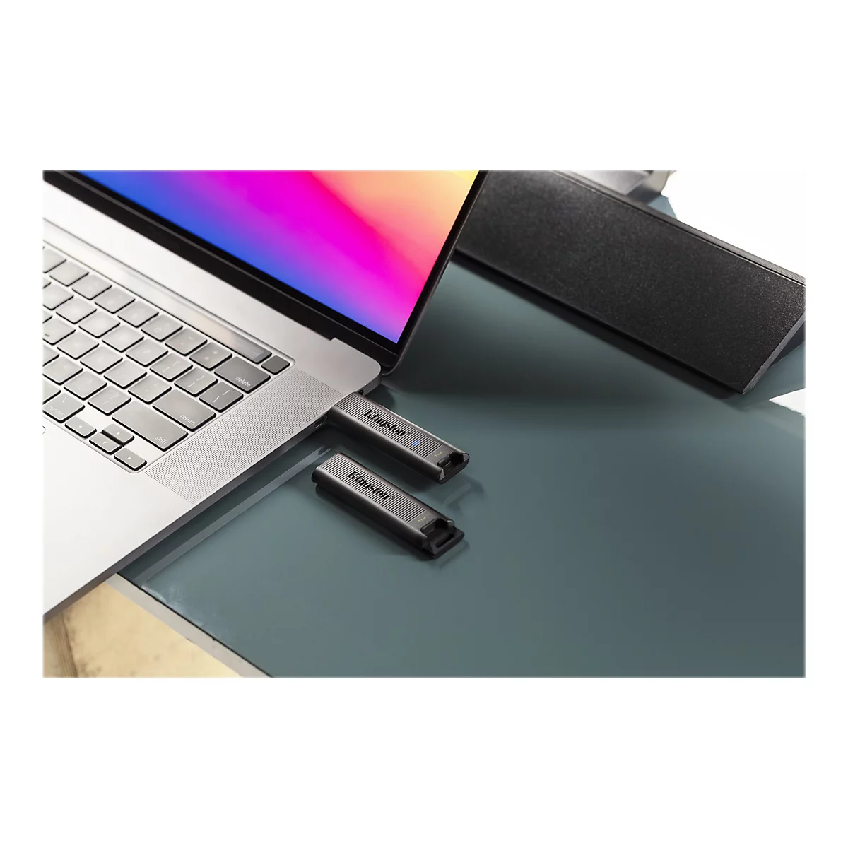 Ein Laptop, zwei USB-Sticks und ein Lautsprecher auf einer glatten OberflÃ¤che. Die USB-Sticks sind mit Kingston beschriftet.