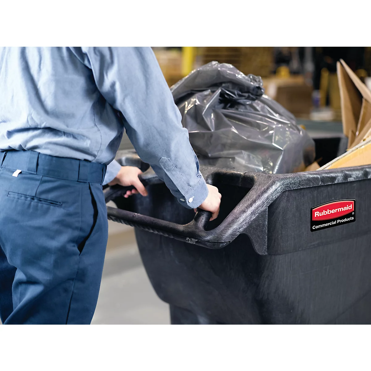 Ein Arbeiter schiebt einen Müllwagen mit einem vollen Müllsack und Kartons.