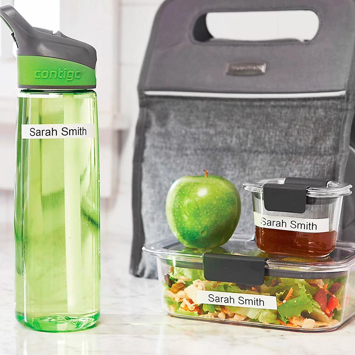 Bouteille d'eau Contigo personnalisée et boîtes à lunch avec étiquettes au nom de Sarah Smith sur un comptoir.