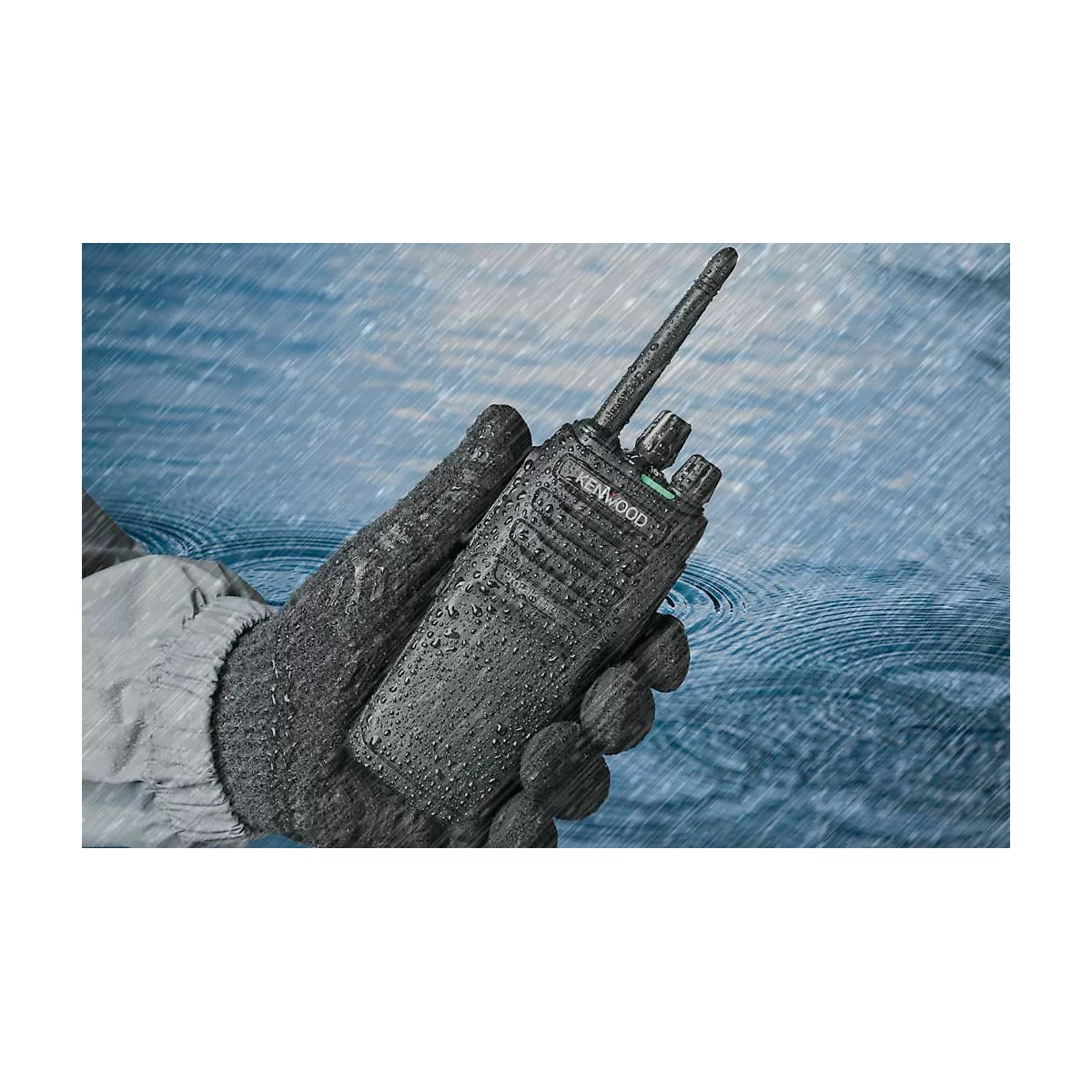 Une radio portative dans un environnement humide, tenue par une main gantée. Des gouttes tombent sur l'appareil.