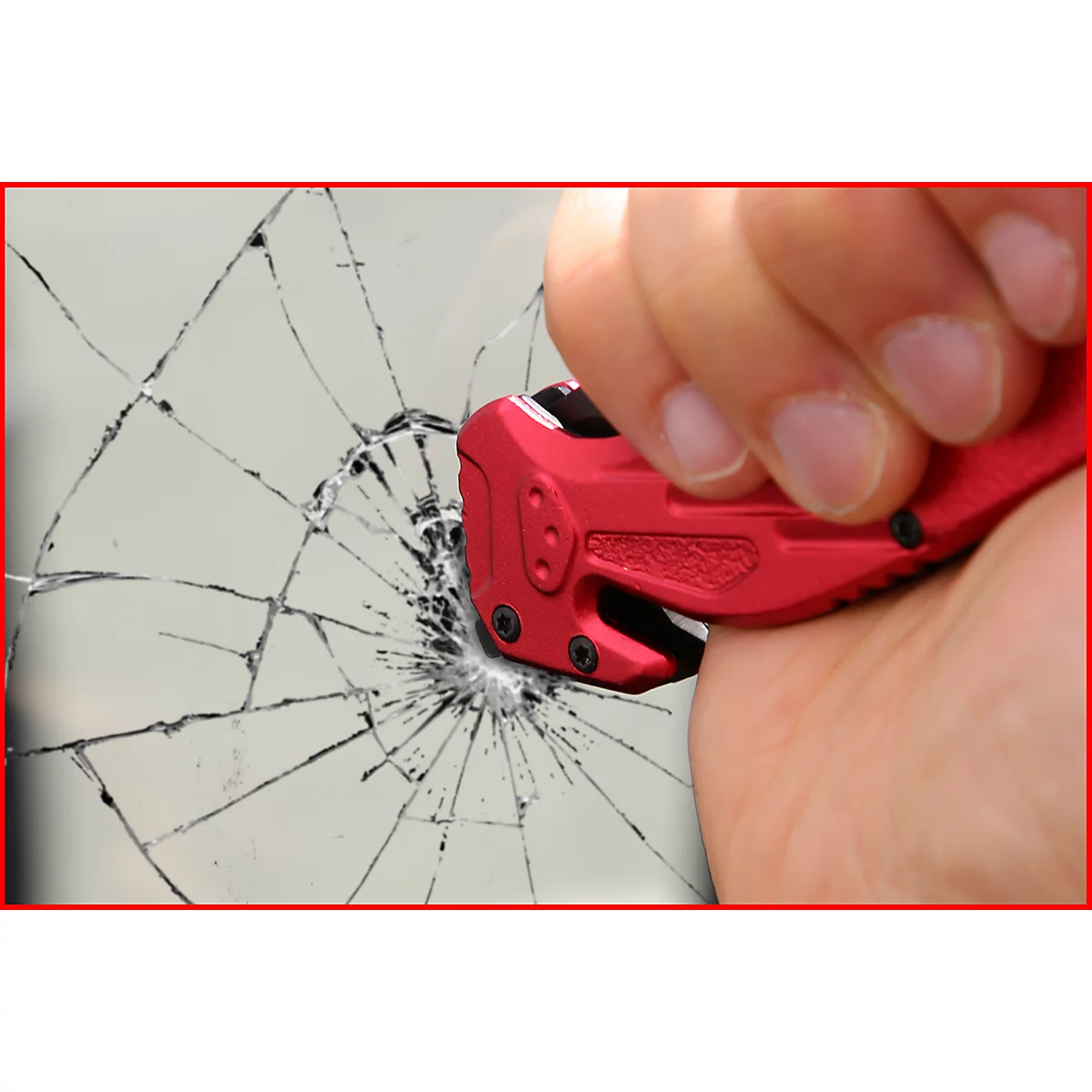 Rotes Werkzeug zerbricht Glas. Ein Finger hält das Werkzeug fest.