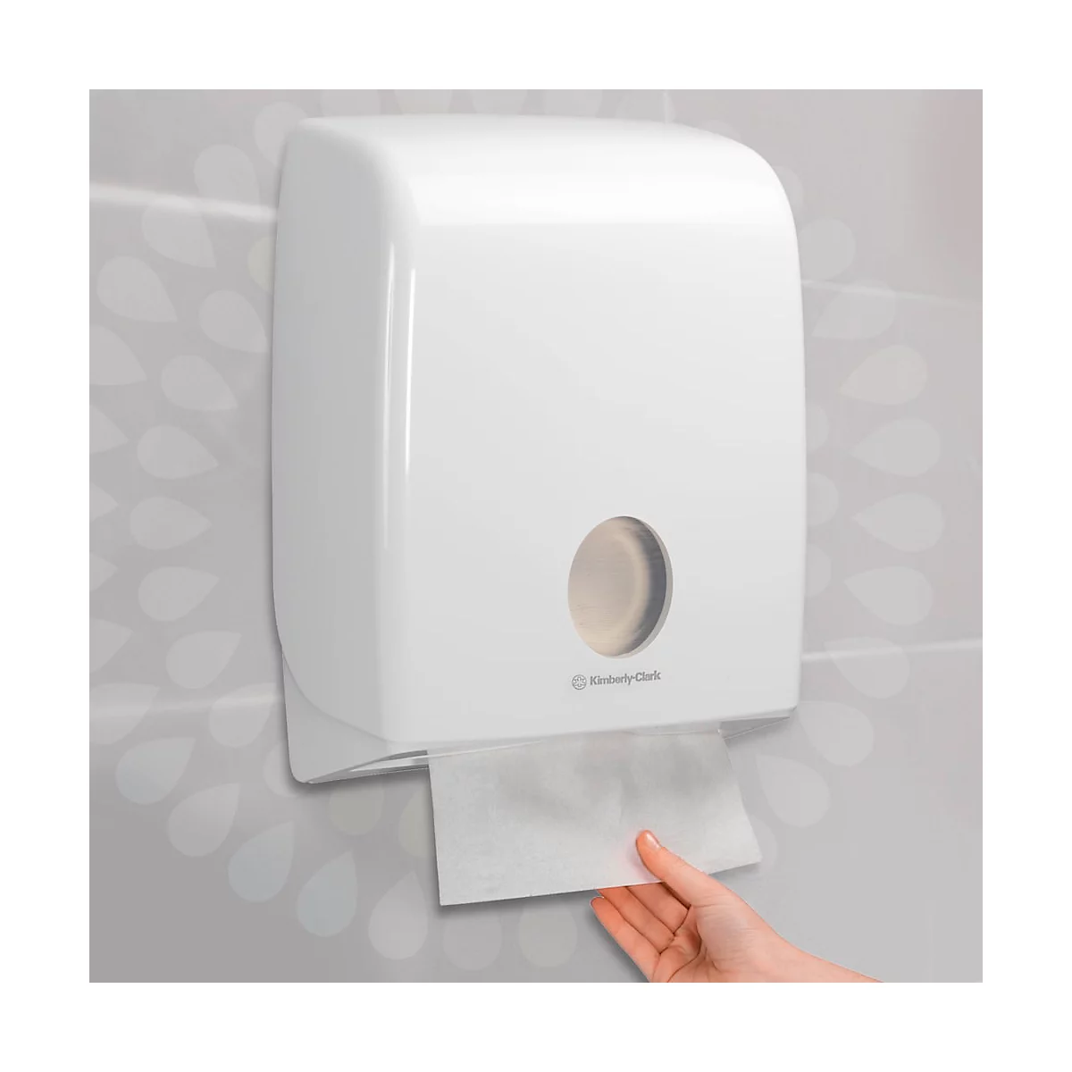 Dispensador de toallas de papel blanco Kimberly-Clark. Una mano saca una toalla de papel.
