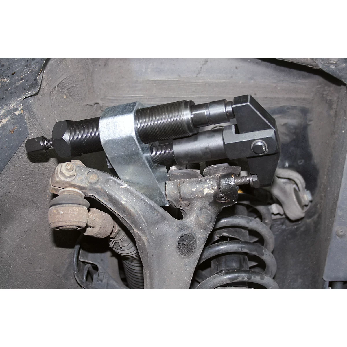 Ein Werkzeug an einem Fahrzeugfahrwerk. Das Werkzeug besteht aus Metall und wird zur Reparatur verwendet.