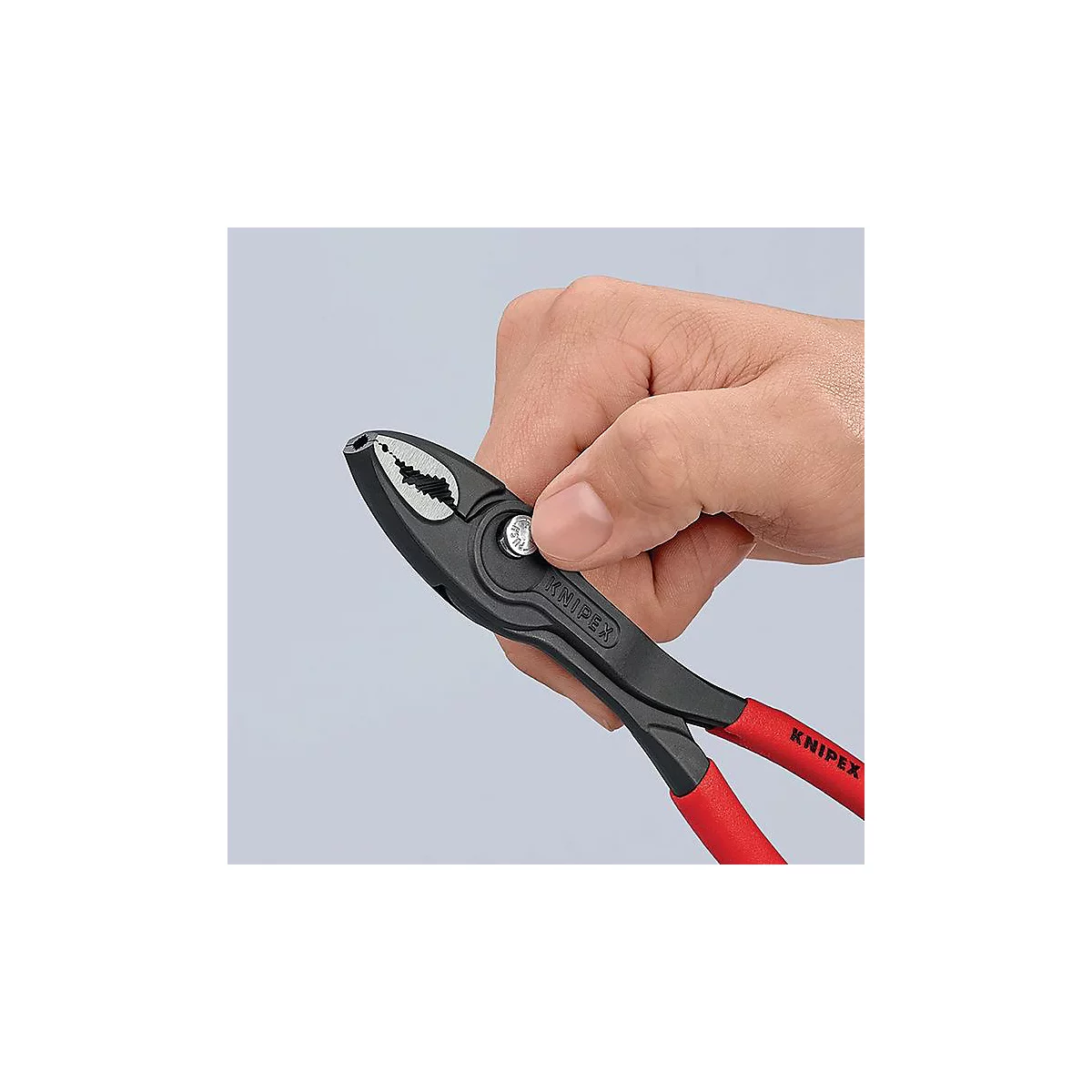 Hand hält schwarze Zange mit roten Griffen. Auf der Zange steht Knipex.