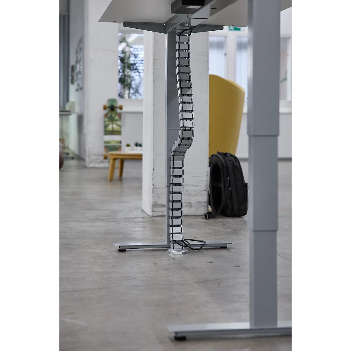 Detailaufnahme einer Kabelführung unter einem höhenverstellbaren Schreibtisch.Graue Kabel werden elegant in einer Schiene geführt.