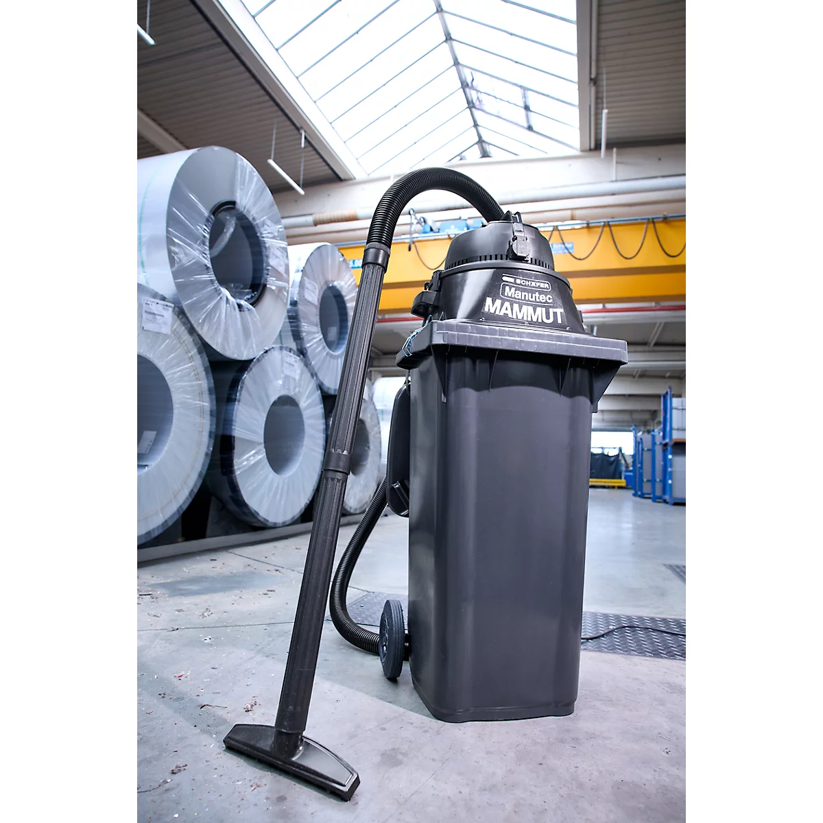 Industriesauger Marutec MAMMUT in einer Lagerhalle mit aufgestapelten Metallrollen im Hintergrund.