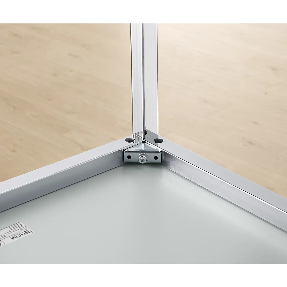 Nahaufnahme einer Eckverbindung aus Metall. Drei silberne Metallprofile treffen sich an einem Winkel, der durch eine Halterung verstärkt wird.