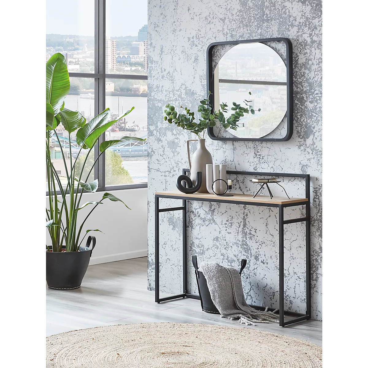 Dekorative Konsole mit Spiegel, Pflanzen und Dekoration. Ein Fenster im Hintergrund zeigt einen Ausblick auf die Stadt.
