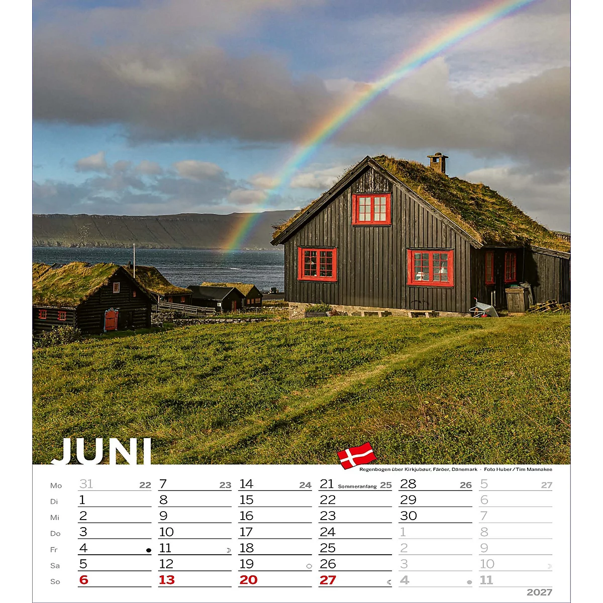 Un arc-en-ciel enjambe une maison avec un toit en herbe et des encadrements de fenêtres rouges. Au premier plan, une prairie, à l'arrière-plan, la mer et les montagnes.
