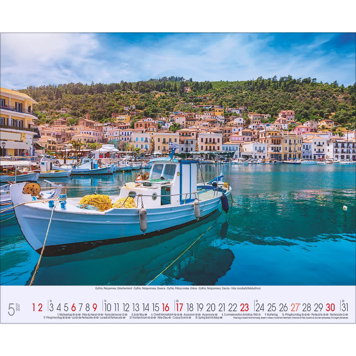 Un bateau devant une ville côtière avec des maisons colorées et des collines verdoyantes. En premier plan la date.