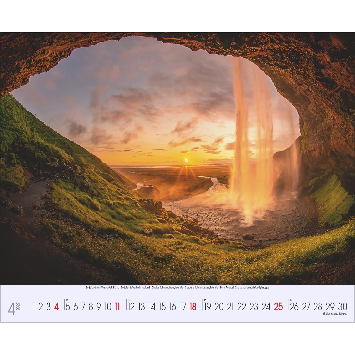 Vue à travers une arche rocheuse sur une cascade au coucher du soleil. Le ciel est orangé-jaune, l'eau brille.