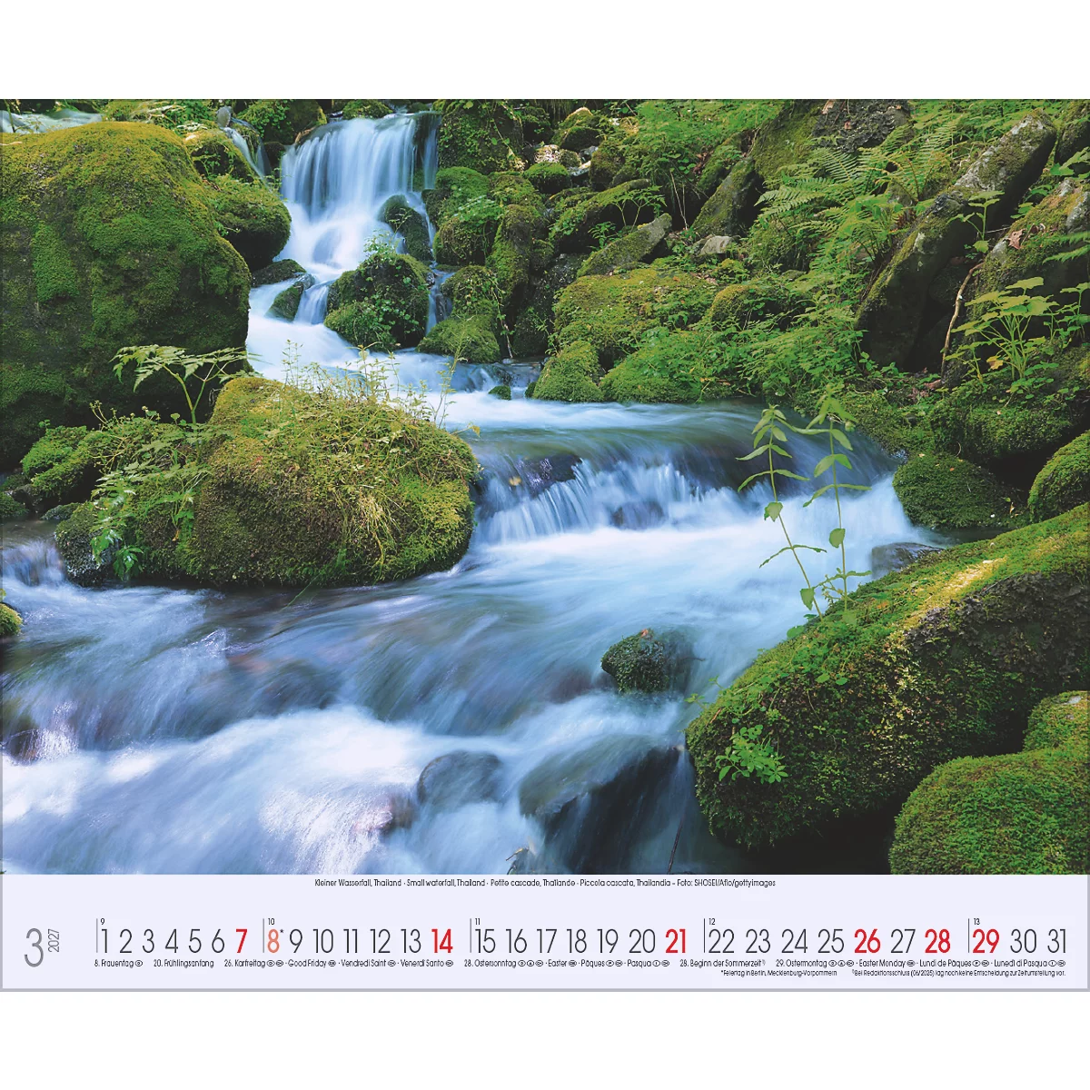 Eau courante d'une cascade entre des rochers couverts de mousse, un tableau de calendrier au premier plan.