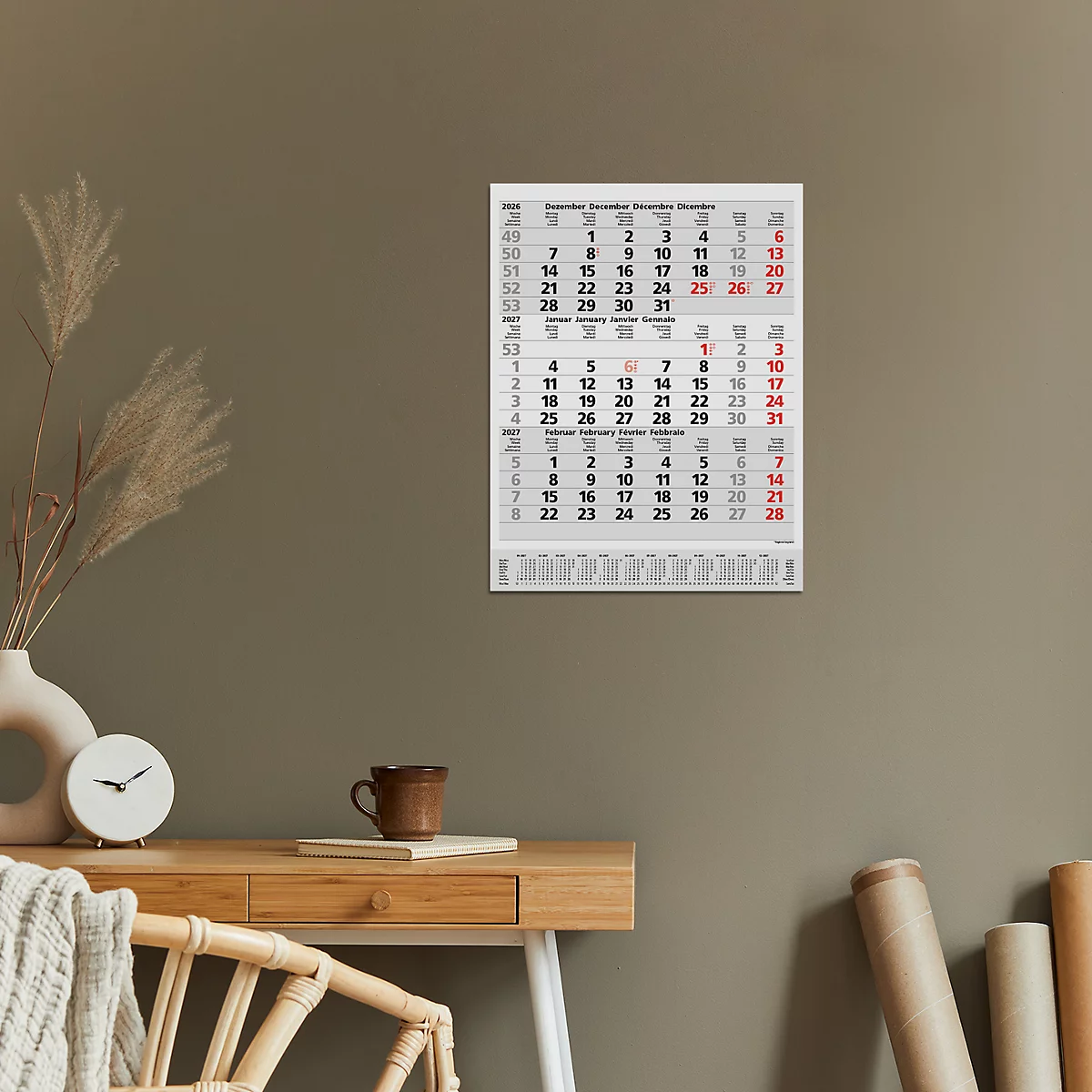 Un calendrier mural avec des dates et des chiffres en rouge et noir. Un bureau avec des décorations est visible au premier plan.