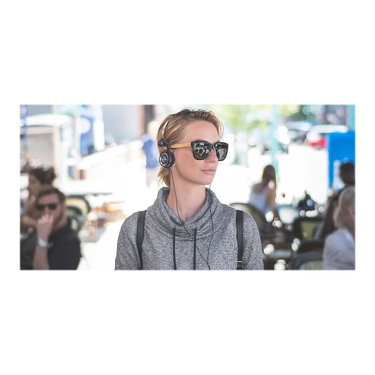 Junge Frau mit Sonnenbrille und KopfhÃ¶rern, Blick zur Seite.
