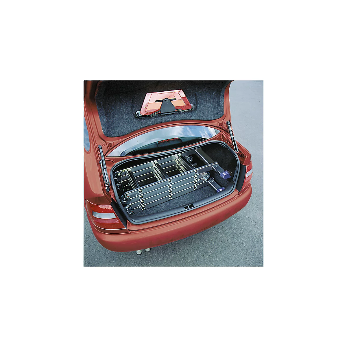 A red station wagon with an open tailgate containing a folded ladder. A warning triangle is attached.