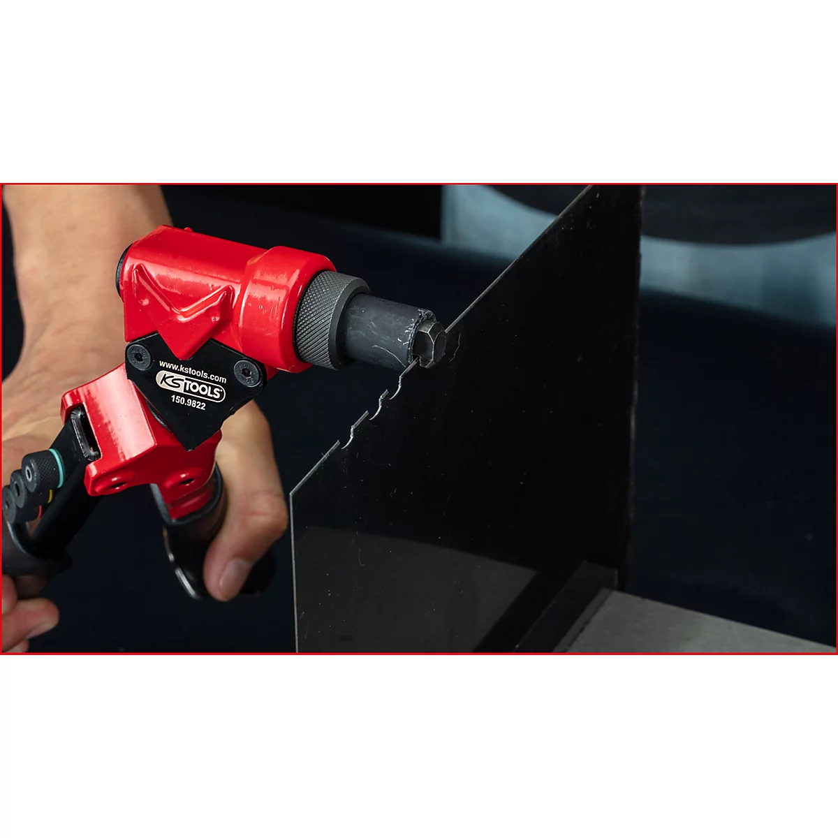 Rote Handnietzange von KS Tools wird verwendet, um eine Kante an einem schwarzen Metallblech zu bearbeiten.