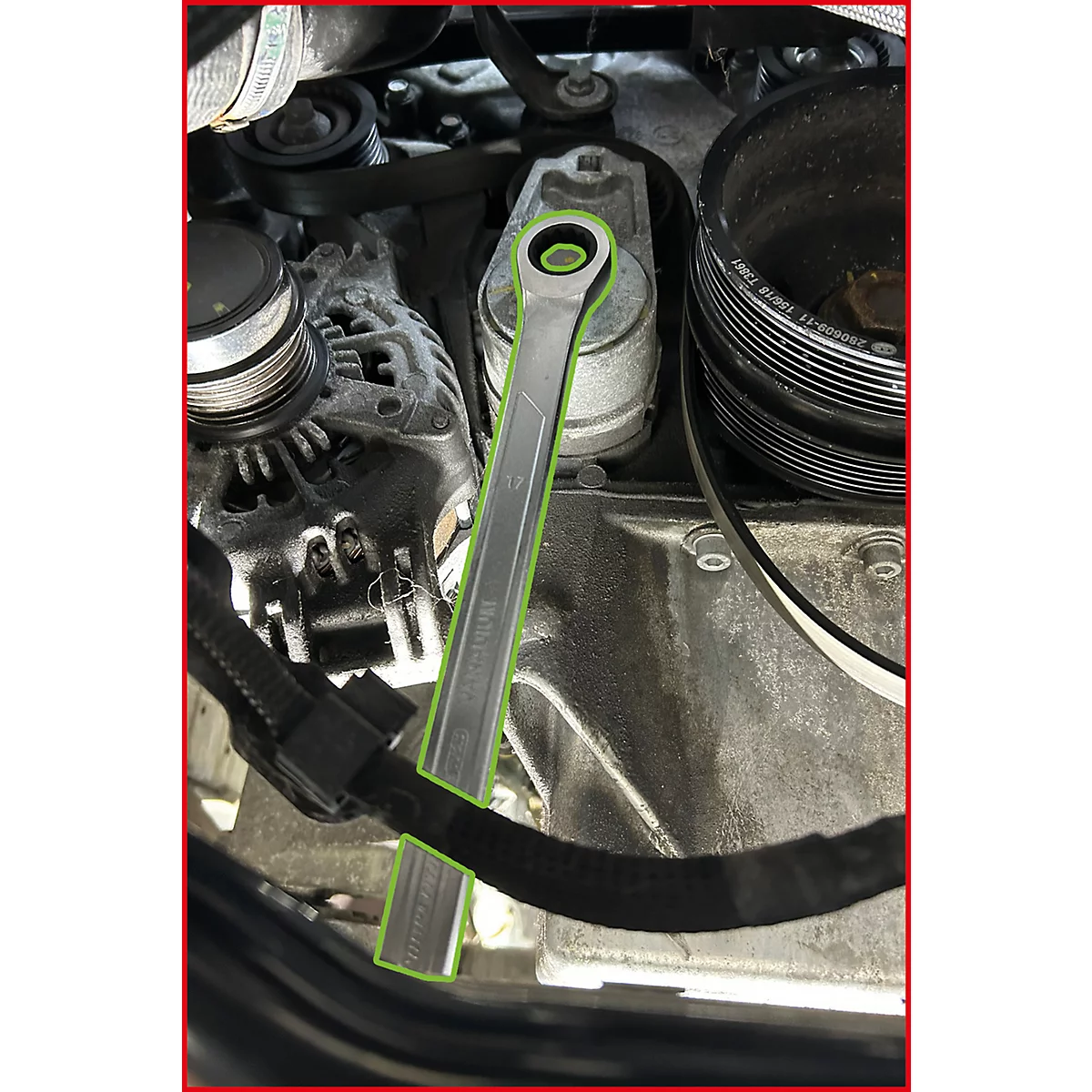 Ein Ringschlüssel setzt an einem Riemenspanner im Motorraum eines Autos an.