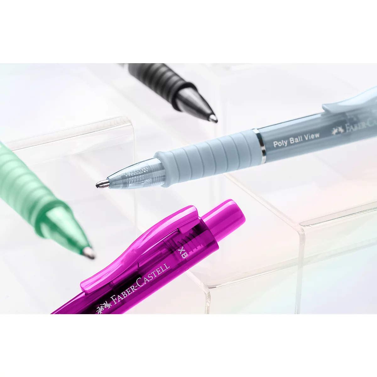 Mehrere bunte Faber-Castell Kugelschreiber liegen auf einer transparenten Ablage.
