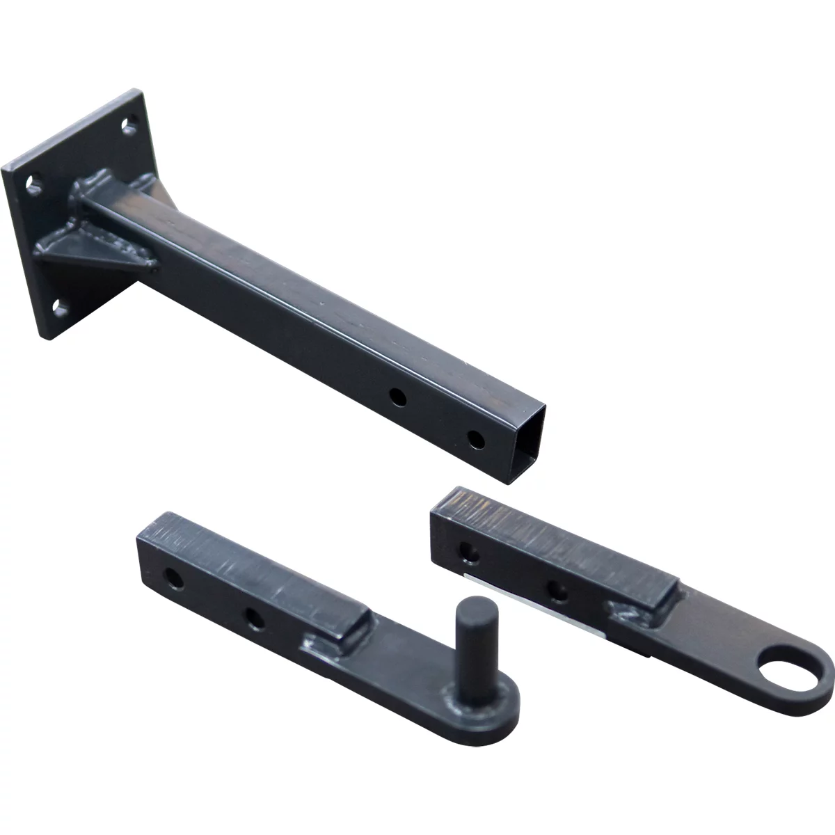 Mehrere schwarze Metallteile für Anhängerkupplung, u.a. ein quadratischer Träger mit Löchern und ein Teil mit Öse.