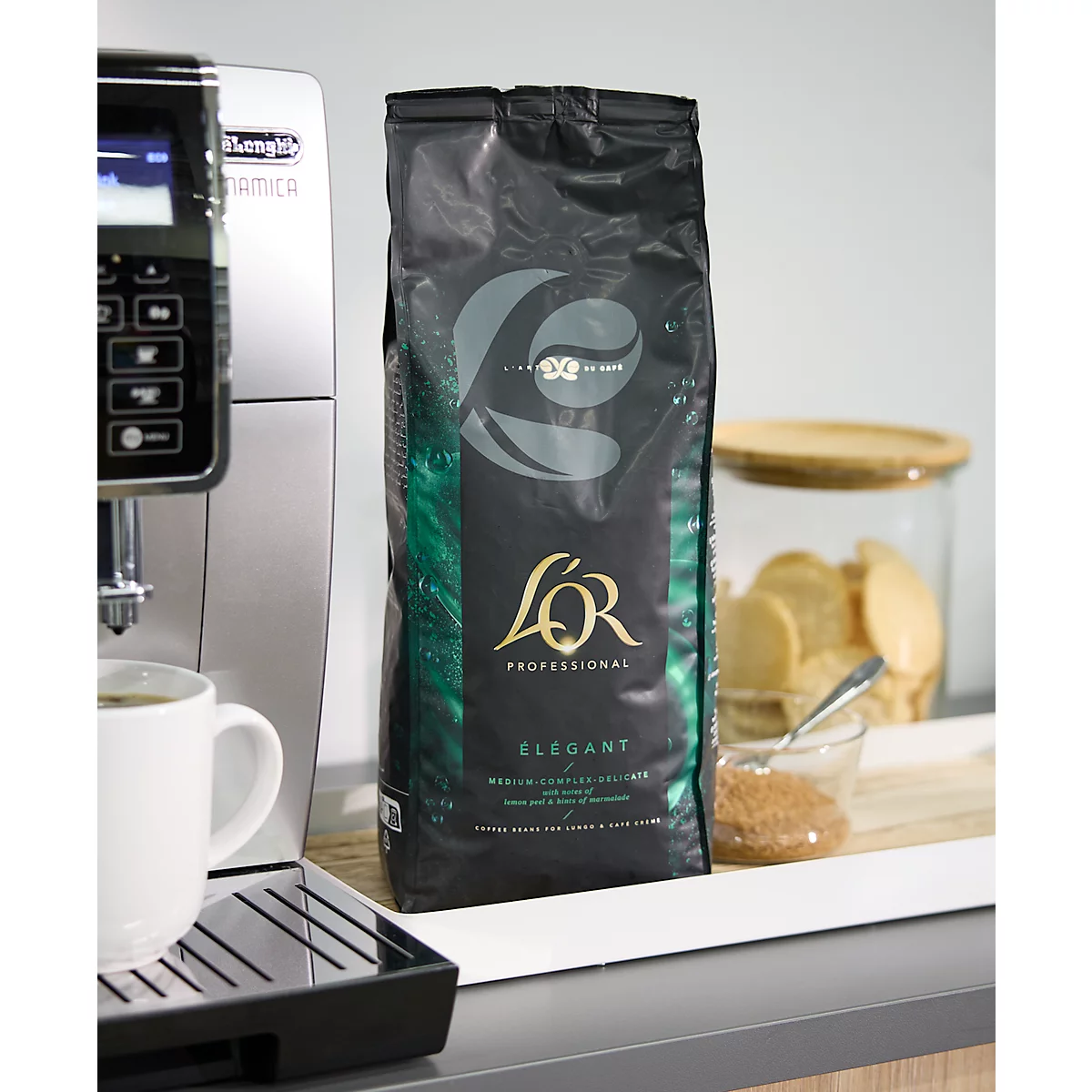 Kaffeebohnenbeutel mit L'Or-Logo neben Kaffeemaschine und Tasse.