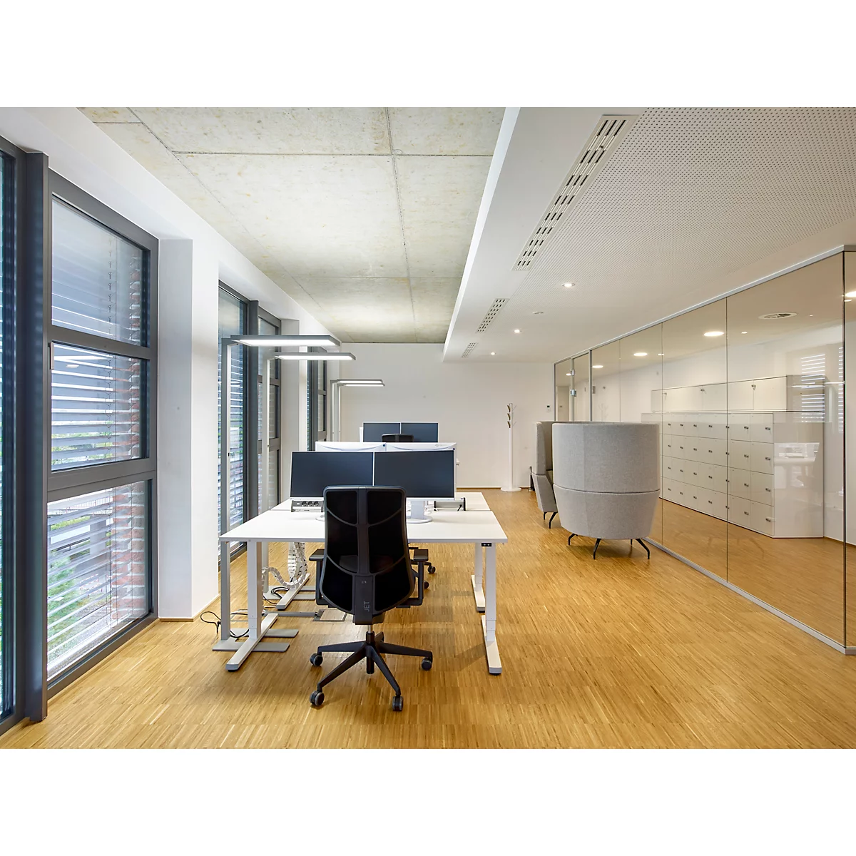 Espace de bureau lumineux avec des bureaux, des chaises et des façades vitrées. Plancher en bois, parois vitrées et éclairage moderne.