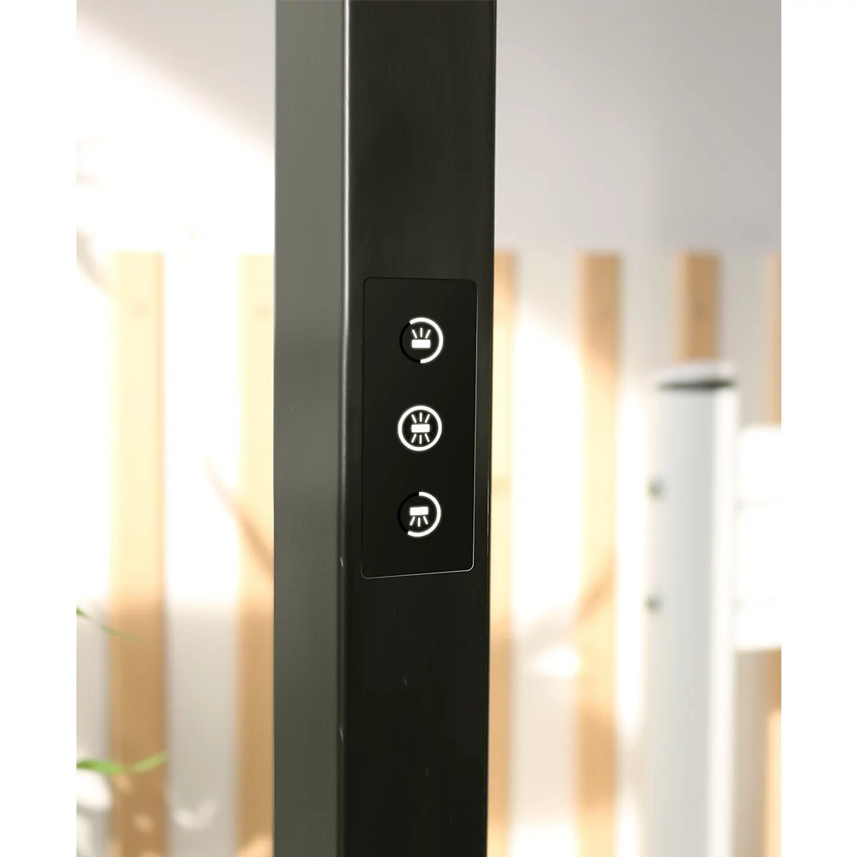Gros plan sur un panneau de commande noir sur un poteau sombre avec trois icônes tactiles éclairées.