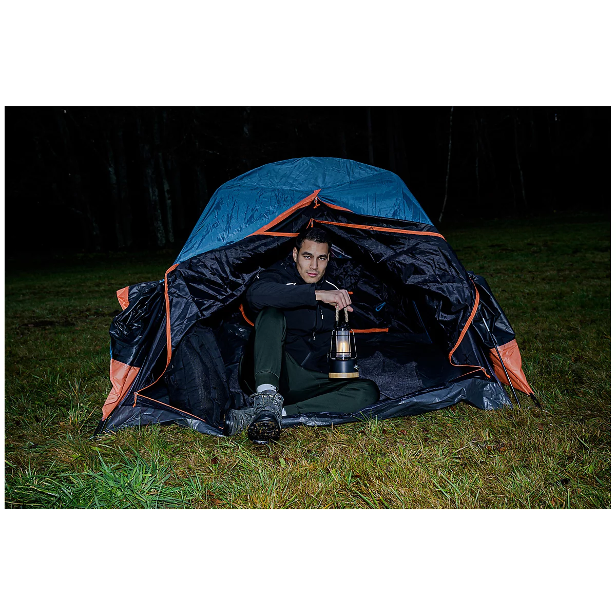 Une lampe portable moderne avec un panier en fil métallique noir. La base est en bois clair, avec un port USB visible. Un câble noir sort de la lampe.