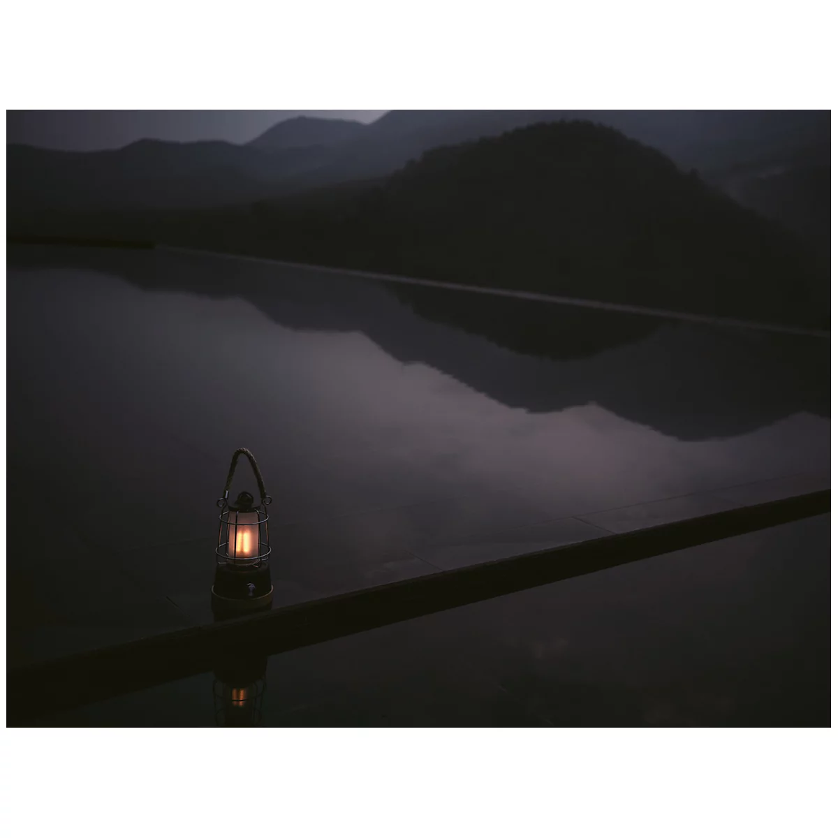 Lampe noire et blanche avec un couvercle en verre transparent et une base en bois, ornée d'une poignée tressée.