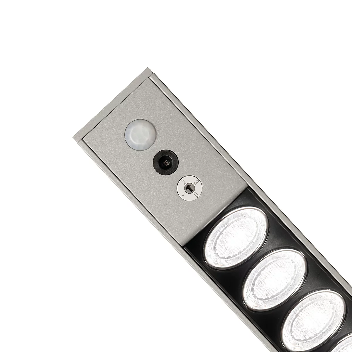 Gros plan sur un luminaire allongé doté d'un détecteur de mouvement intégré, d'un capteur et de trois LED circulaires.