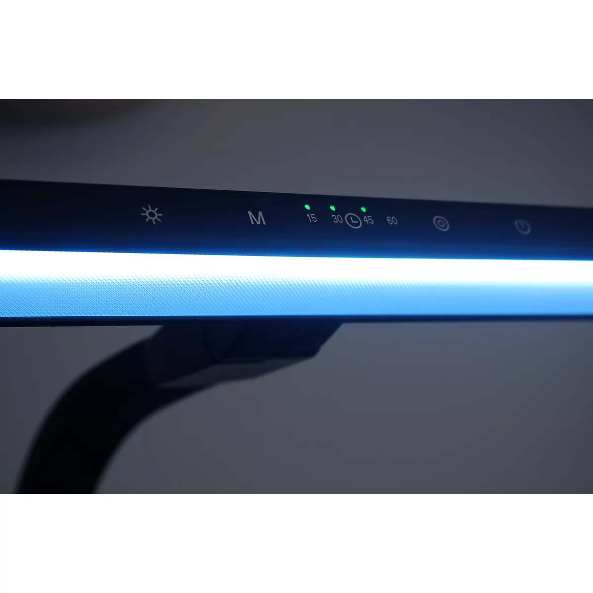 Gros plan sur le panneau de commande d'une lampe de bureau avec des voyants LED verts allumés et des icônes.