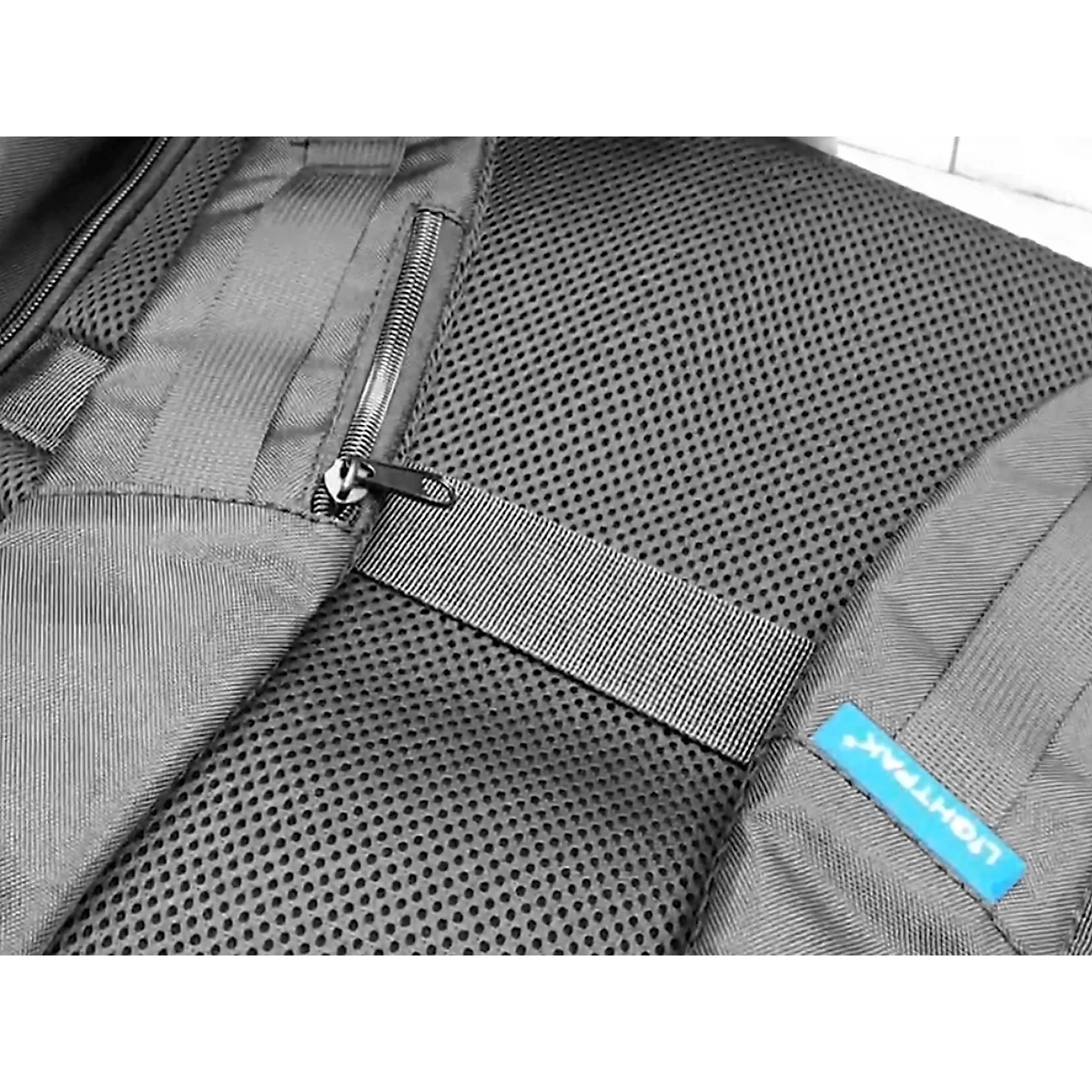 Nahaufnahme eines grauen Rucksacks. Reißverschluss, Mesh-Gewebe und Stoffbänder. Ein blaues Label mit LIGHTPAK-Schriftzug.