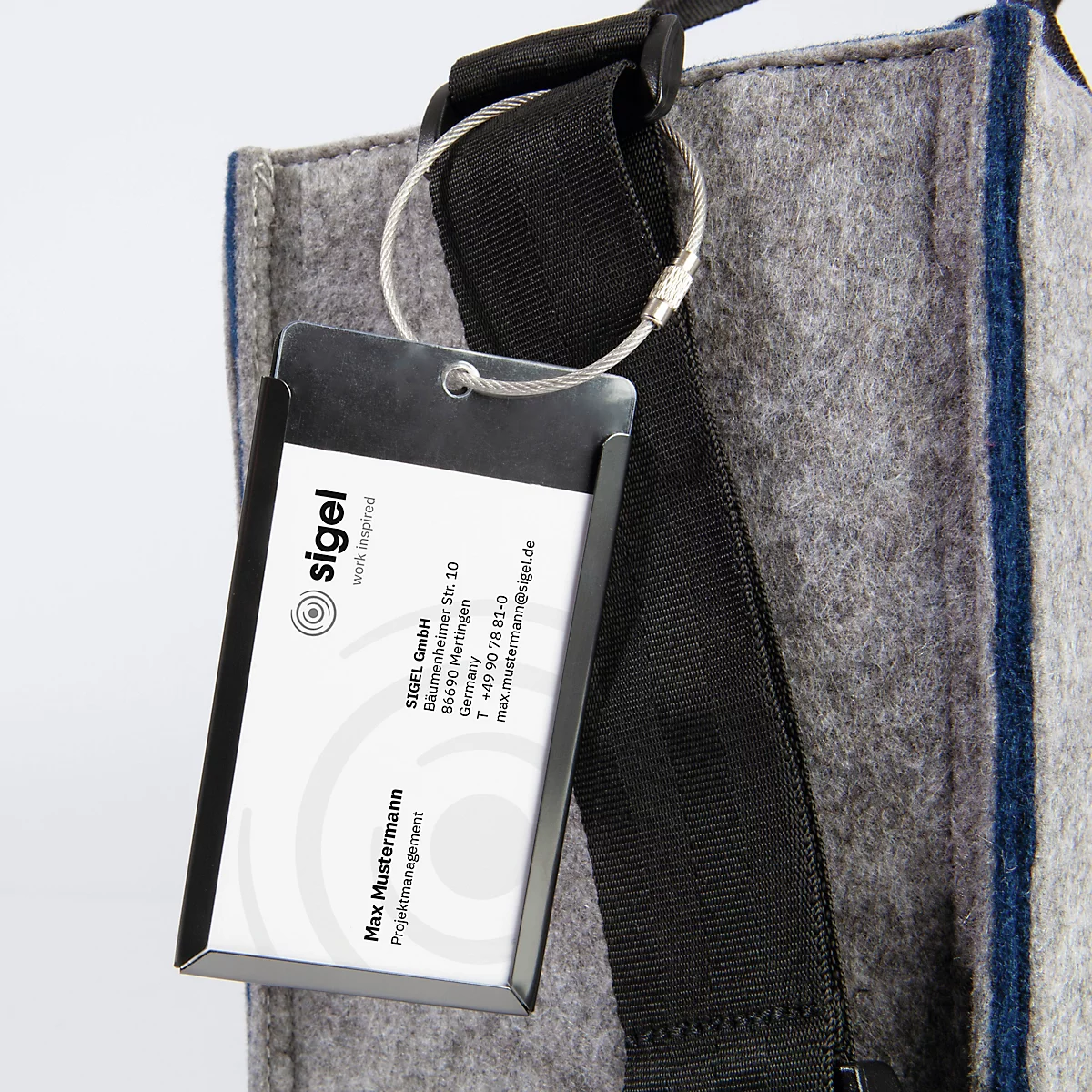 Graue Filztasche mit schwarzem Henkel und Namensschild. Das Schild enthält Firmenlogo, Adresse und Kontaktdaten.
