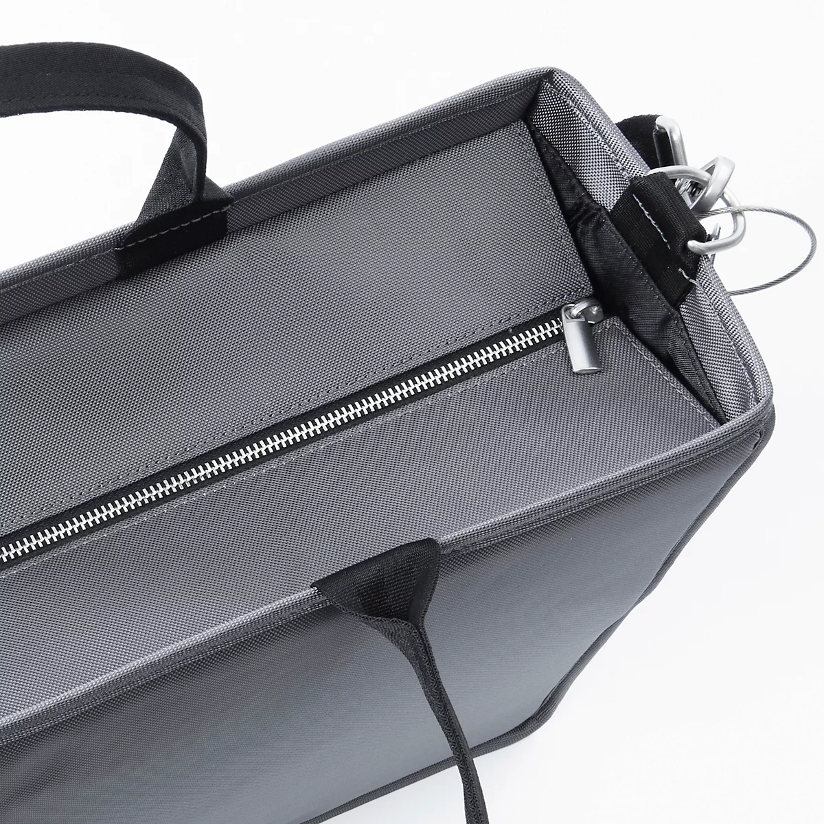 Graue Handtasche mit Reissverschluss und Griffen, Nahaufnahme.