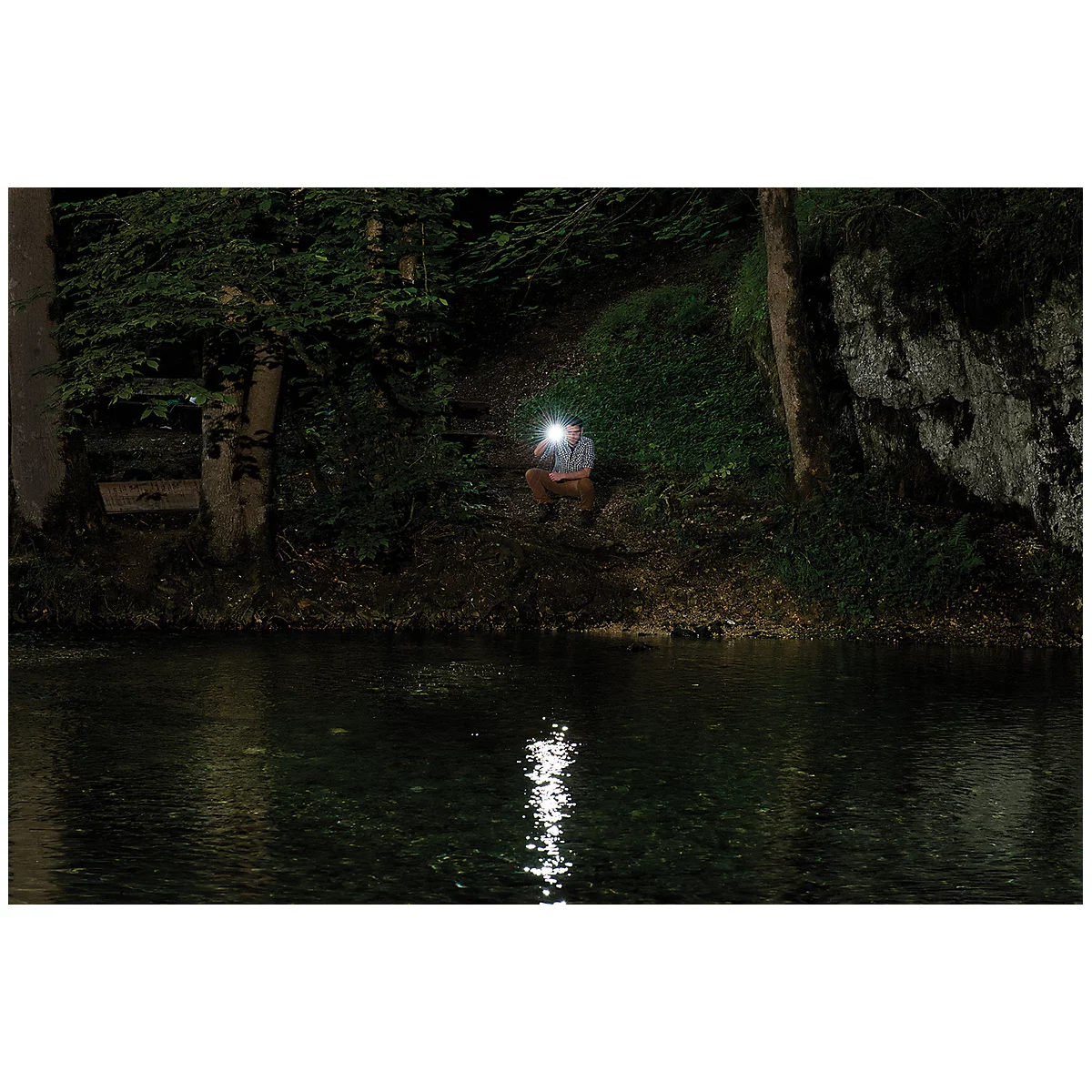 Black flashlight with yellow button, side clip, and carrying strap.