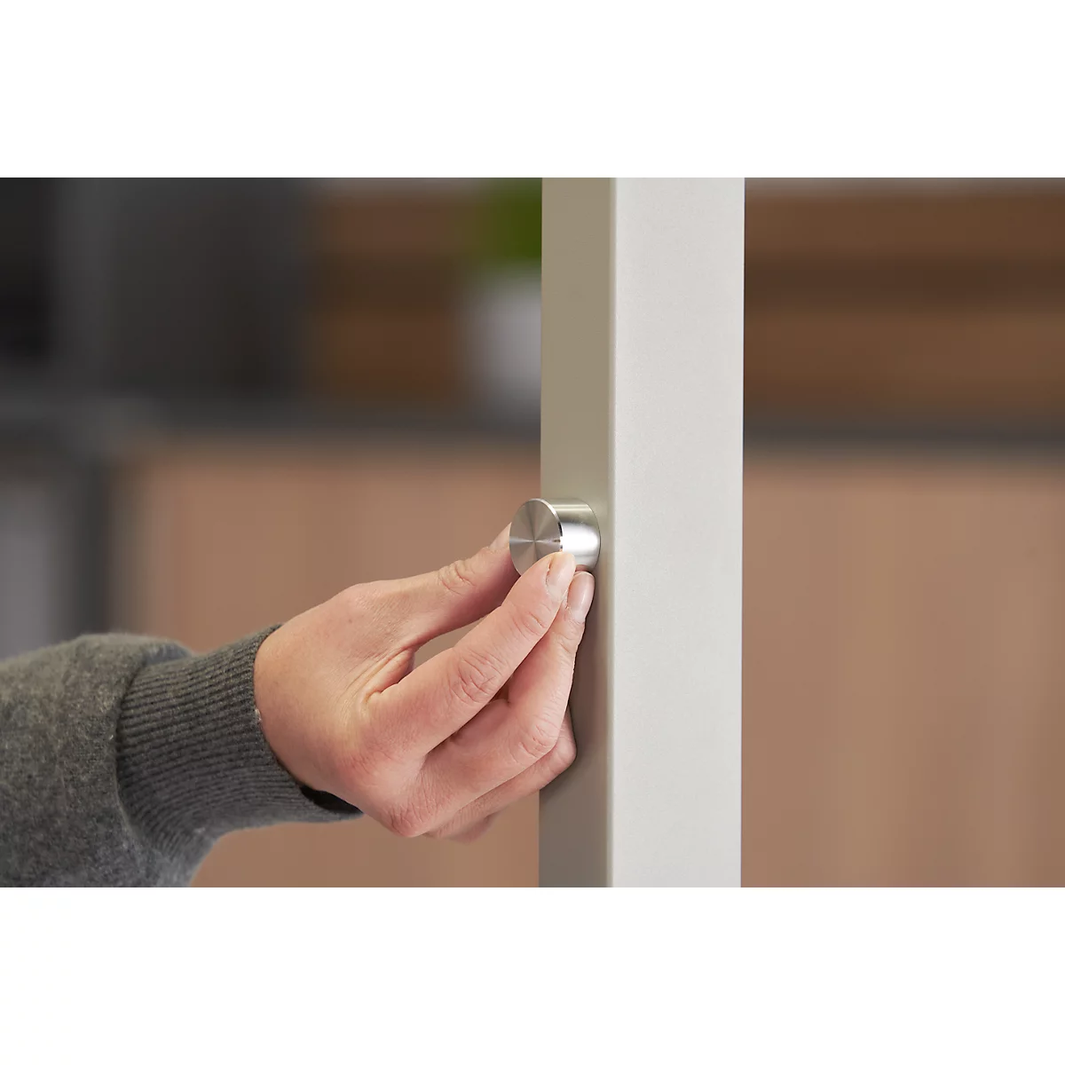 Nahaufnahme einer Hand, die einen silbernen Knopf an einer weißen Säule dreht.