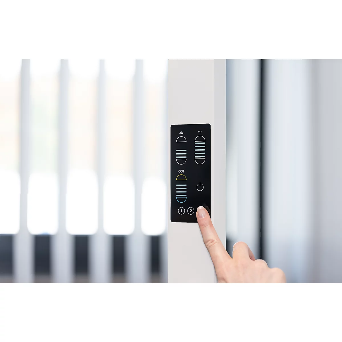 Eine Hand berührt ein schwarzes Bedienfeld mit Symbolen. Im Hintergrund ist ein Fenster mit Jalousien zu sehen.