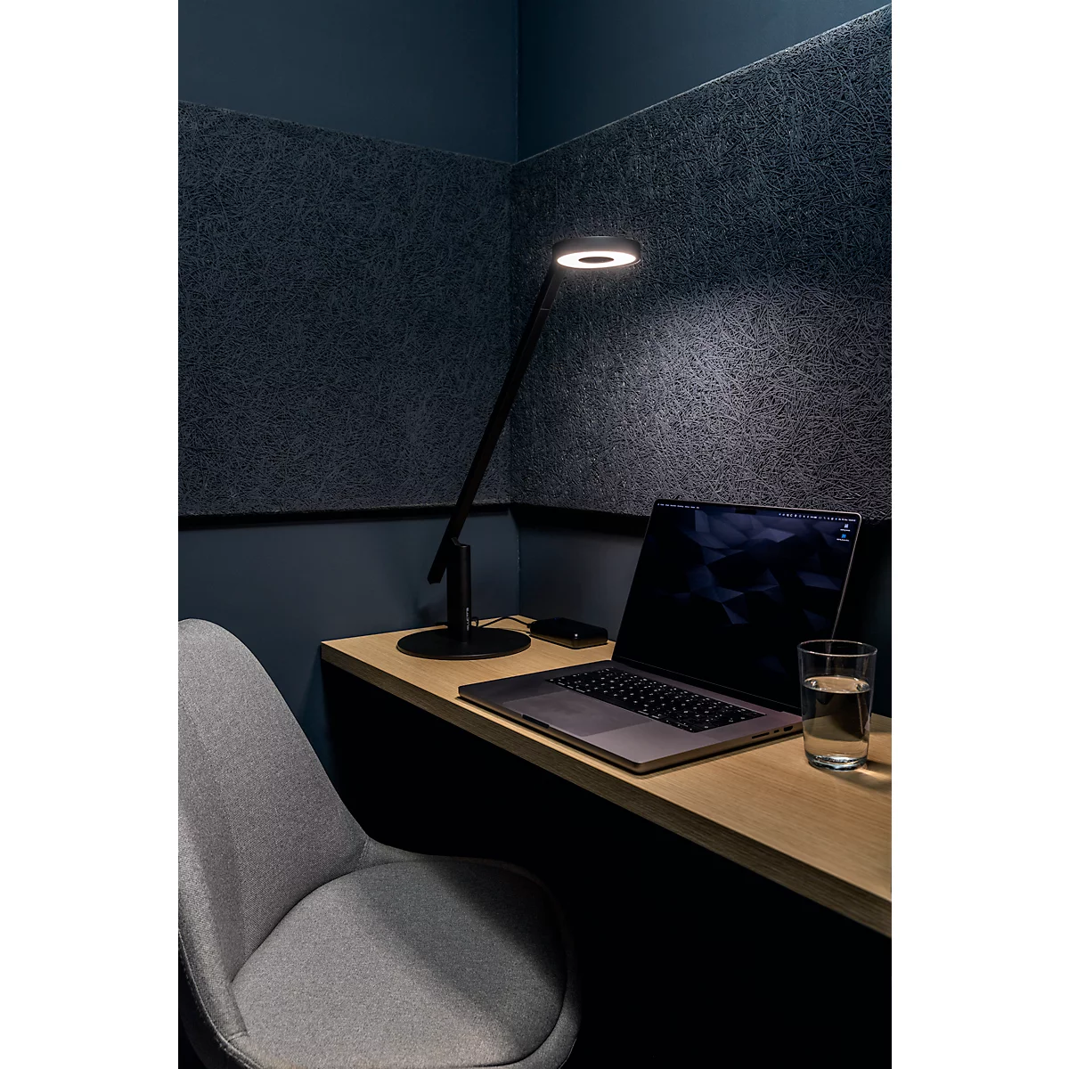 Desk with lamp, laptop, glass of water and chair. Dark background.