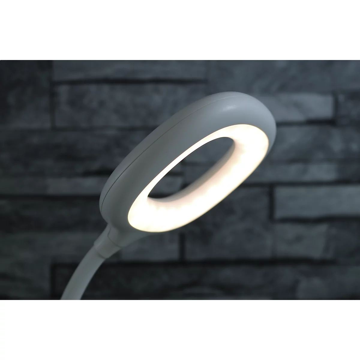 Nahaufnahme einer weißen LED-Schreibtischlampe mit einem leuchtenden, kreisförmigen Lampenkopf.