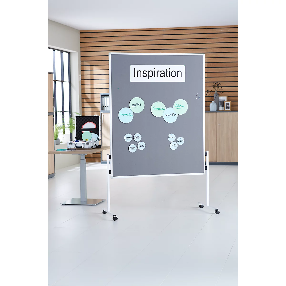 Grijs prikbord met "Inspiration" opschrift en notitielabels, voor een houten wand. Verrijdbare poten.