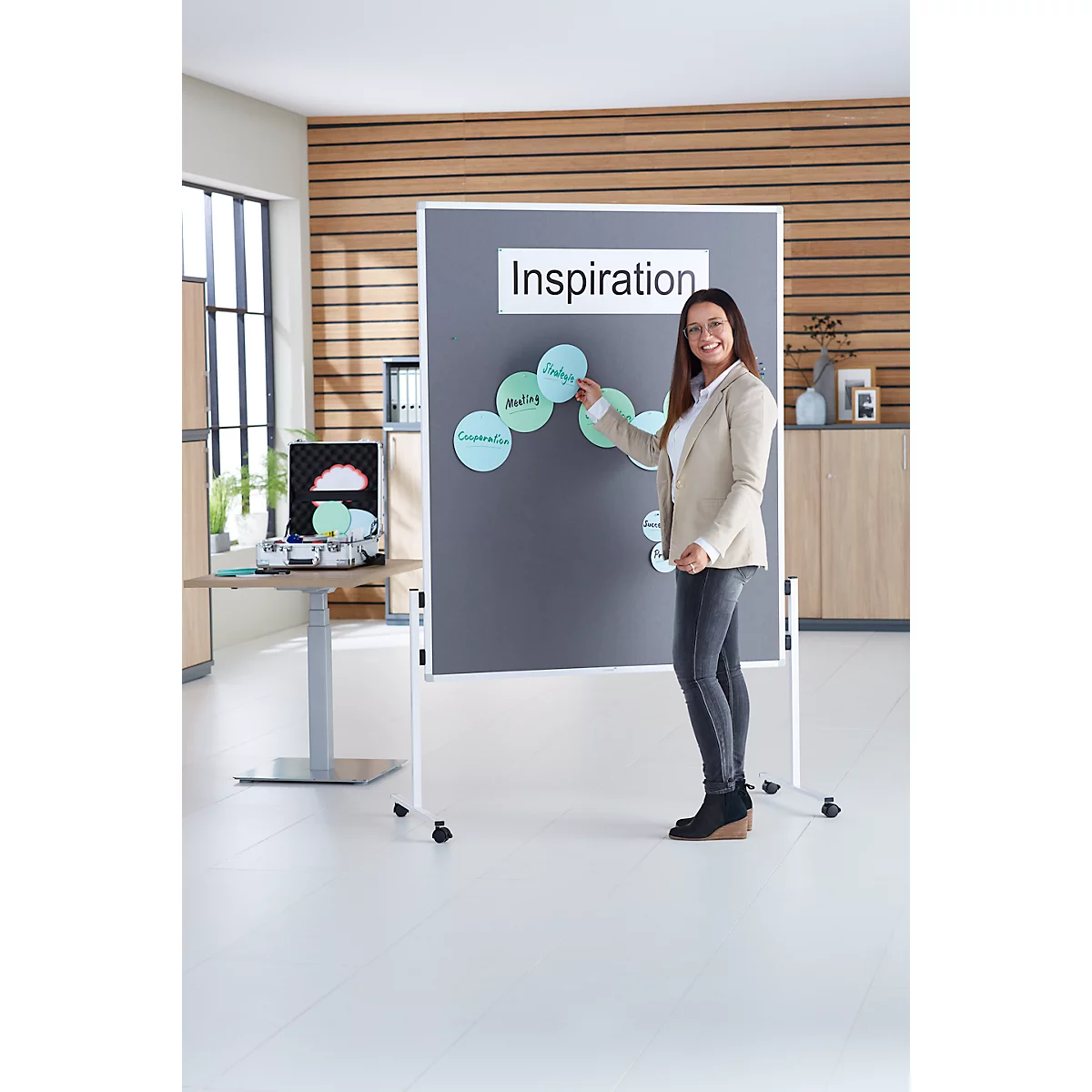 Een vrouw staat voor een presentatiebord met het woord 'Inspiratie'. Ze wijst naar cirkels met termen als 'Idee'.