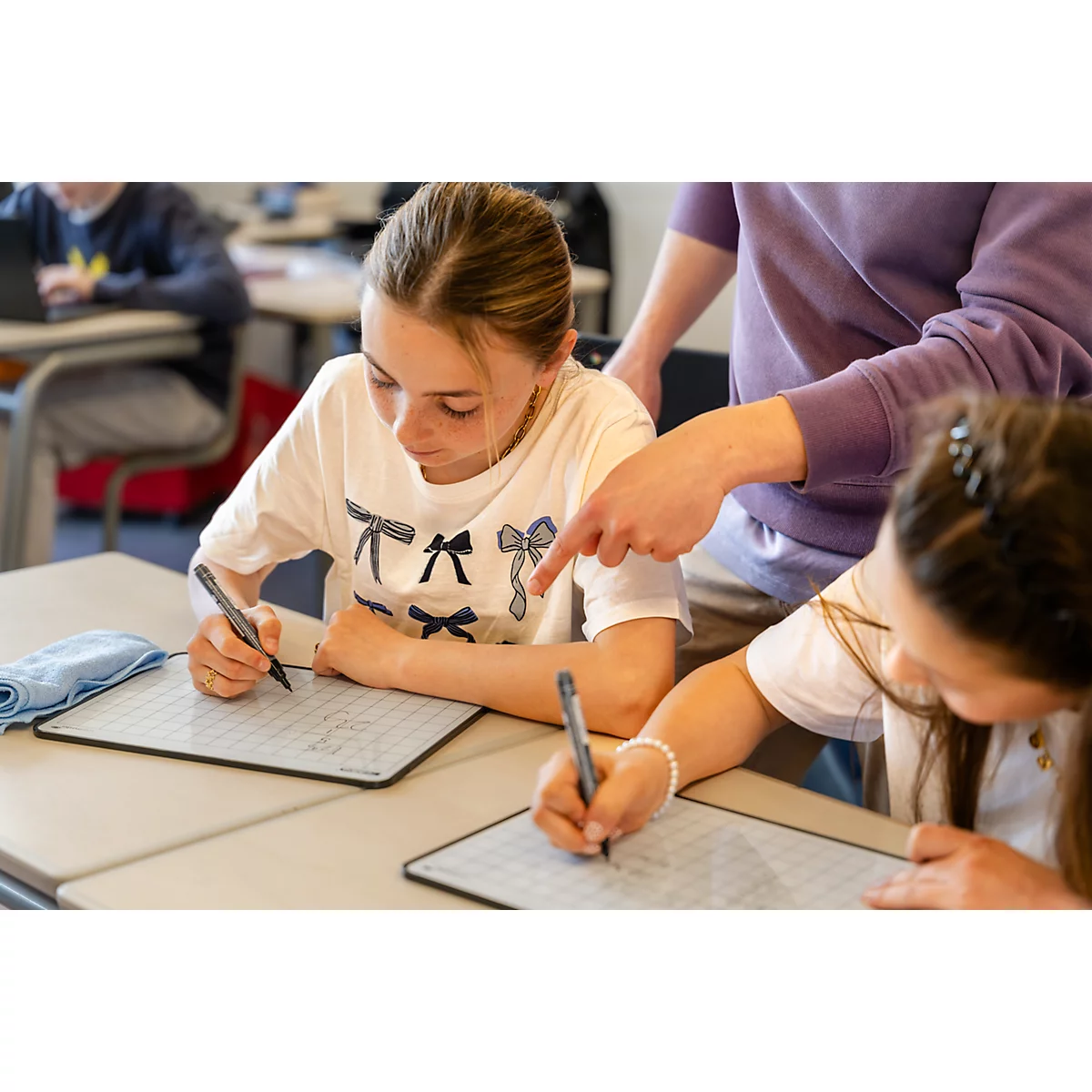 Schülerin schreibt konzentriert mit einem Stift auf ein weißes Whiteboard-Tablet im Unterricht.