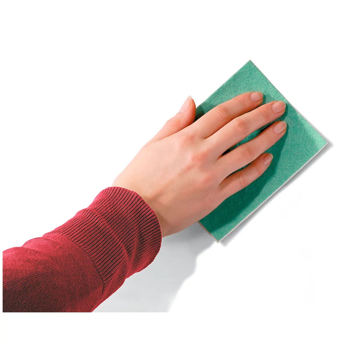 A hand holds a green sponge and wipes over a white surface.