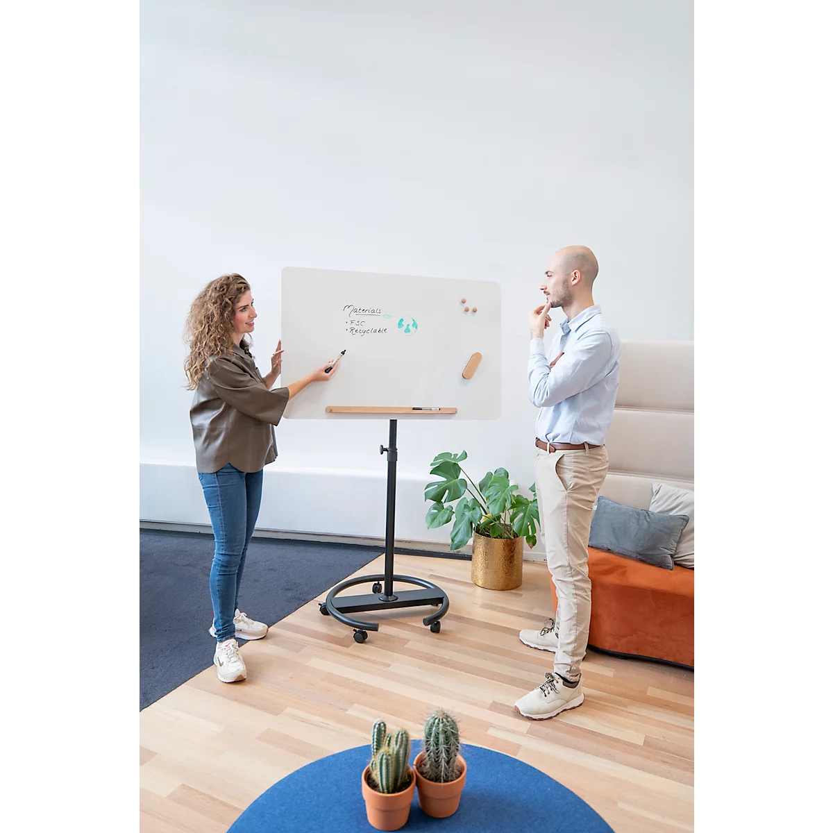 Een vrouw legt iets uit op een whiteboard, een man staat ernaast en denkt na.